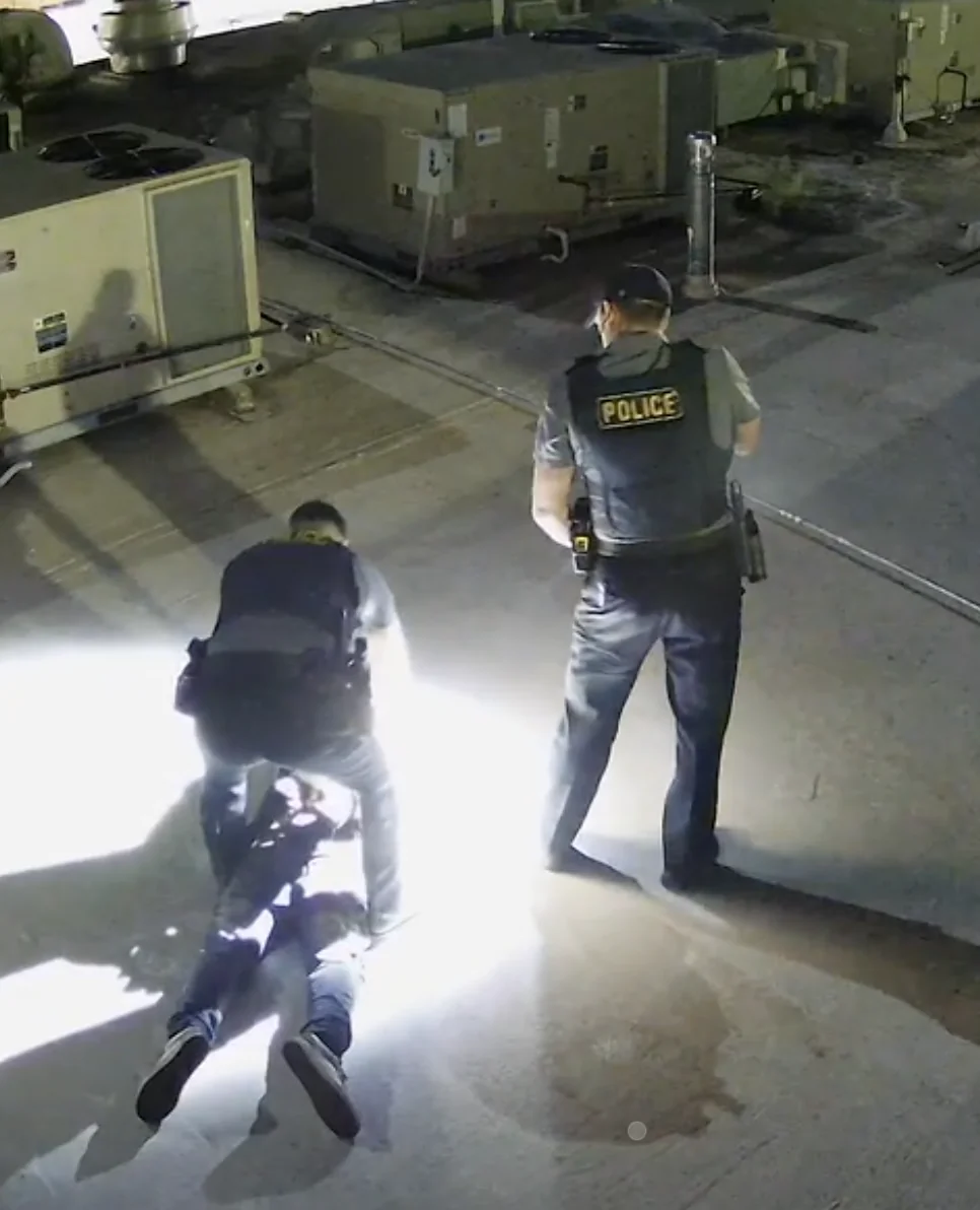 Police officers detaining a trespasser on a monitored commercial rooftop at night